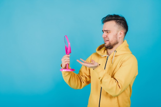 the guy in the yellow sweatshirt looks at himself in the pink mirror