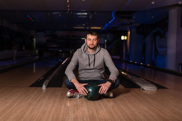 The guyl sits and keeps the ball in the bowling club