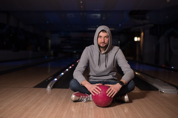 The guyl sits and keeps the ball in the bowling club