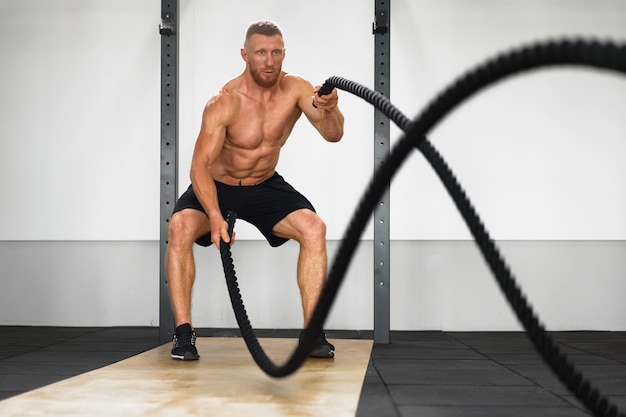 Muscular man working out on the battle ropes in a gym, premium image by  rawpixel.com / Teddy Rawpixel