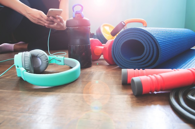 Gym and fitness equipment at home with woman using smartphone