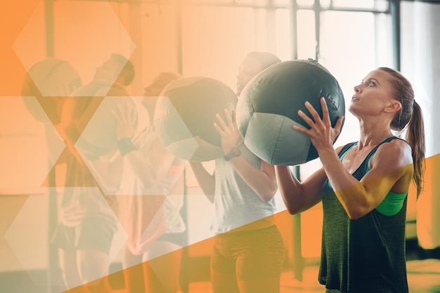 Foto la palestra fitness e la donna lanciano la palla medica per l'esercizio fisico e l'allenamento in classe atleta insieme per l'impegno nella sfida del potere e muscoli forti al centro benessere con una sovrapposizione di mockup