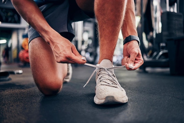 Gym hands and man tie shoes getting ready for workout training or exercise Fitness sports or male athlete in fitness center preparing for running cardio or bodybuilding practice in health studio