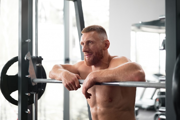 Gym man leunend barbell rust na harde training.