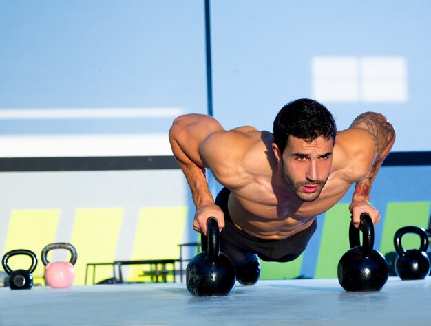 Gym man push-up strength pushup with Kettlebell 