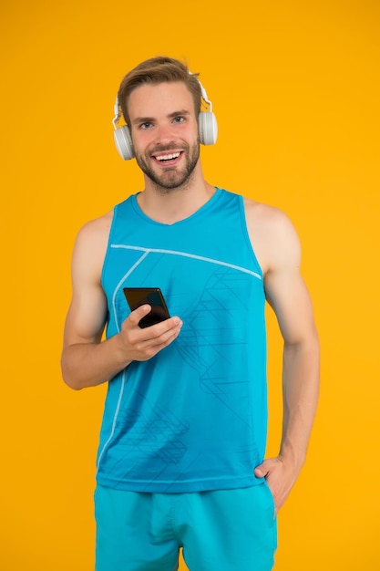 Gym music. Athletic man listen to music on smartphone. Mobile music. Sports playlist. Sport and fitness. Active lifestyle. Health and wellness. Workout motivation. Motivational music. New technology.