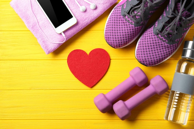 Photo gym stuff phone and red heart on color wooden background cardio training concept