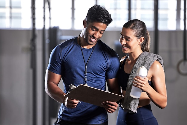 Gym subscription personal trainer and happy client talking and ready to fill in a membership form Fitness coach discussing training workout plan and progress in a health and wellness facility