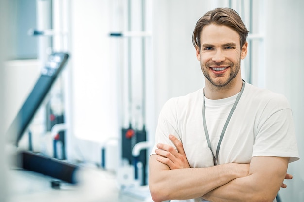 Photo in a gym young man in sportswear sitting on a training device in a gym