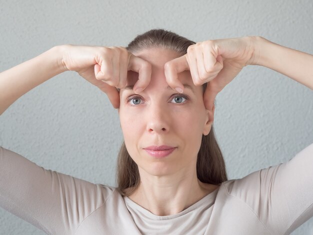 Foto ginnastica per il viso. la donna fa esercizi ringiovanenti per il viso