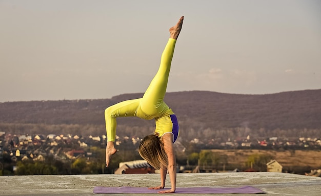 Gymnastiekatleet Het wordt nooit gemakkelijker Flexibel meisje buiten Vrouw die yoga beoefent Spieren uitrekken Fitnesstrainer Vrouw voert gymnastische prestaties uit Je wordt gewoon sterk Acrobatische gymnastiek