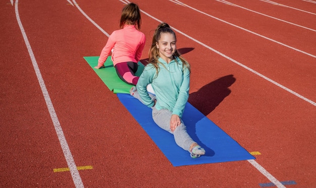 Gymnasts prepare for competition athletes warm up on stadium gym split flexibility children training at school physical lesson teenage girls stretching before training Everything is possible