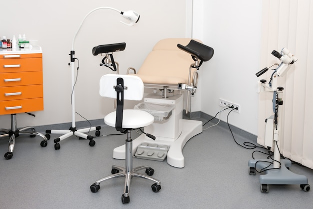 Гинекологический кабинет с креслом и другим медицинским оборудованием в современной клинике