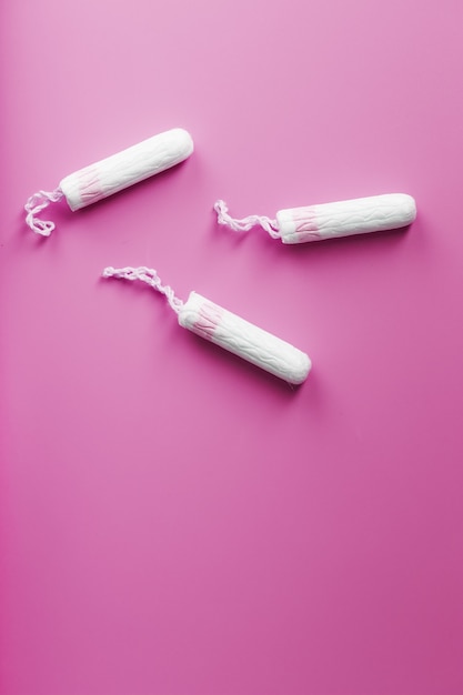 Gynecological tampons on a pink background top view, free space