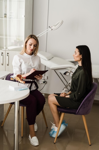 Gynecologist asks young girl about menstrual cycle and writes down information in the questionnaire Consultation with gynecologist and discussion of reproductive health of woman in gynecology clinic