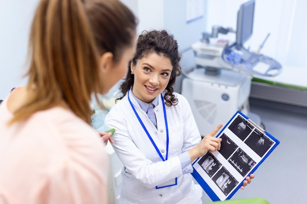 Gynecologist showing a picture with ultrasound to a young woman patient explaining the features of womens health during a medical consultation in the office