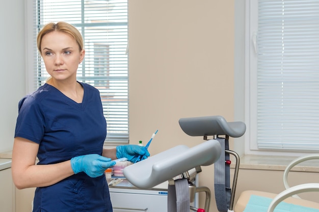 Gynecologist stands at a gynecological chair with brushes for taking an analysis from a patient