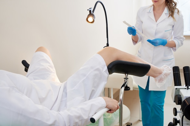 Gynecologist using vaginal swab for STD testing. Woman in gynecological chair