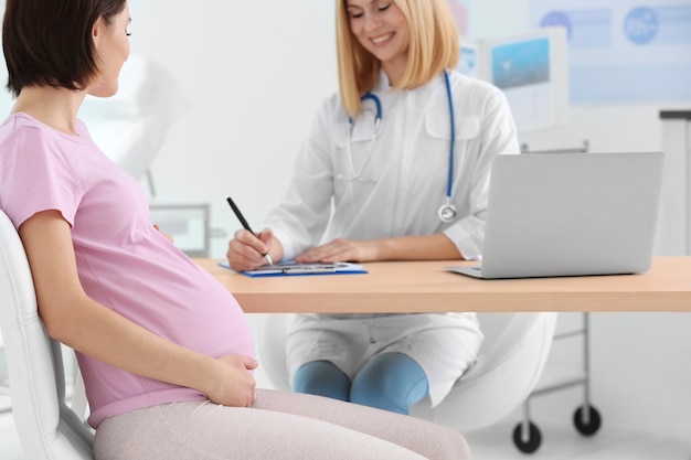 Gynecologist writing prescription to pregnant woman in hospital