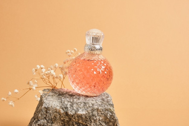 カスミソウの花、ベージュの背景に天然石の銀の帽子と球形のクリスタルピンクのモックアップ空白の香水瓶