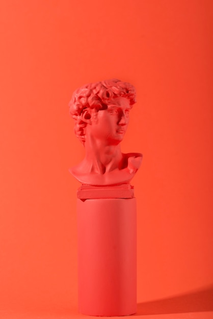 gypsum bust on coral background with geometric shapes