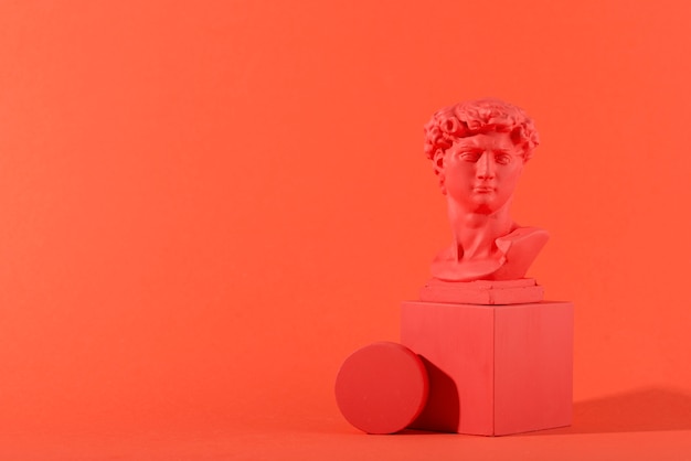 gypsum bust on coral background with geometric shapes