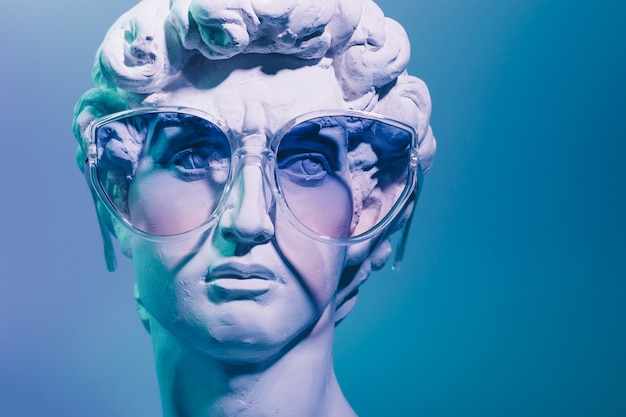 Gypsum copy of the sculpture David Michelangelo in sunglasses on blue background