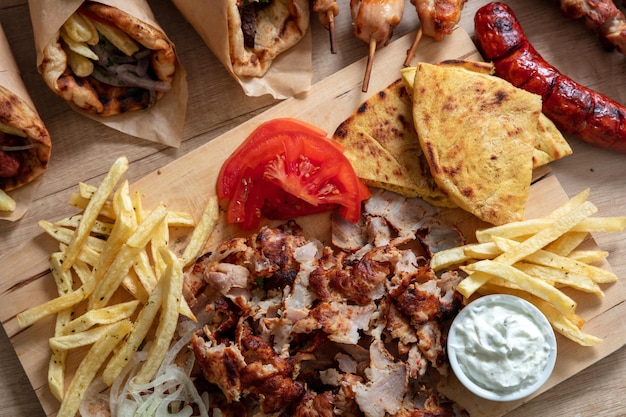 Photo gyro greek sliced meat ethnic dish pita bread tzatziki yogurt on wooden table overhead