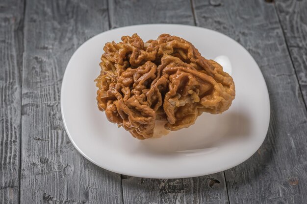 Gyromitra in a white plate on a wooden table