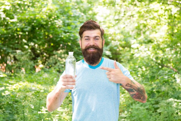 H2O maakt een wandelaar dorstig hipster reiziger drinkwater in bos buiten met zonsondergang natuur op achtergrond Bebaarde man met waterfles fitness portret van bebaarde man gelukkig volwassen man