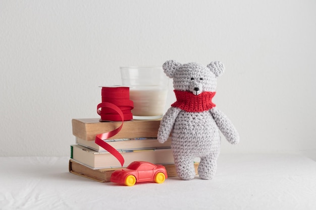 Haak breien schattige teddybeer met boeken en een stuk speelgoed op een witte tafel