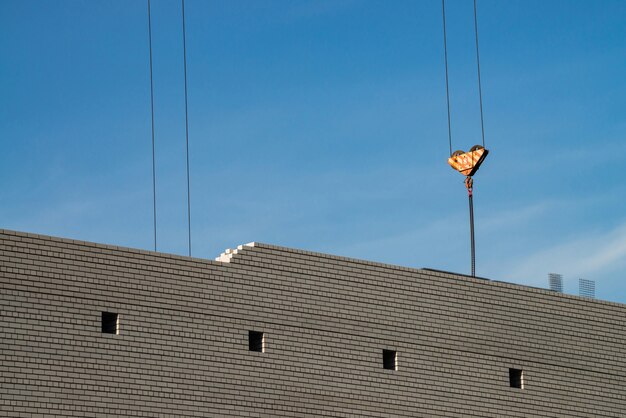 Haak van torenkraan boven onvoltooid gebouw in bouwplaats