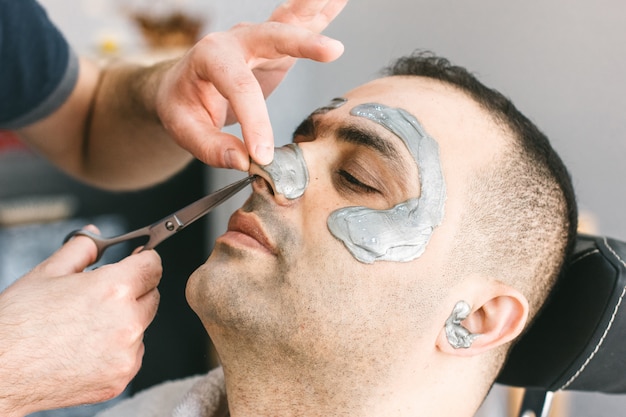 Haar knippen in de neus van een man. Mannelijk gezicht waxen. Kapper verwijdert haar door zich van het gezicht van de Turkse man te verwijderen.