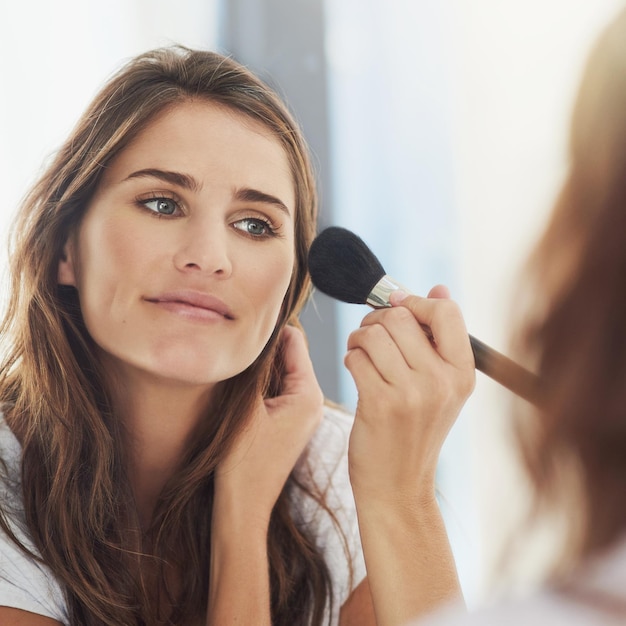 Haar make-up blenden voor een natuurlijke look Shot van een mooie jonge vrouw die make-up aanbrengt met een borstel