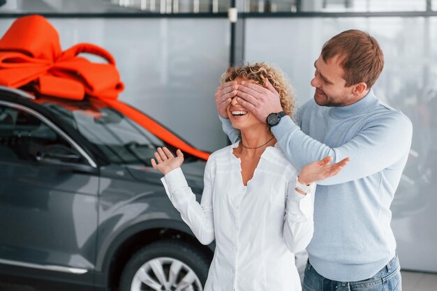 Haar ogen sluiten met de handen Echtgenoot maakt cadeau voor zijn vrouw Moderne nieuwe auto