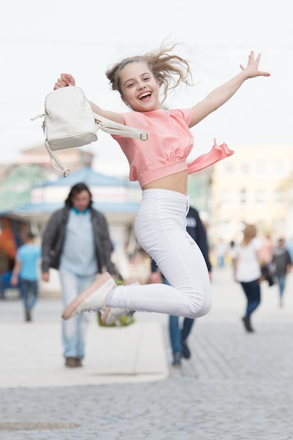 Haar stijl is veel meer casual. Gelukkig klein meisje springen in casual en comfortabele outfit. Klein schattig kind glimlachend in casual stijl. Casual en comfortabel.