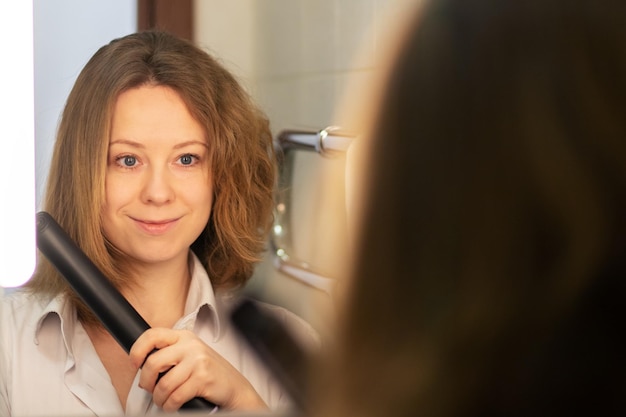 Haar straightening vrouw met voor en na in de badkamer