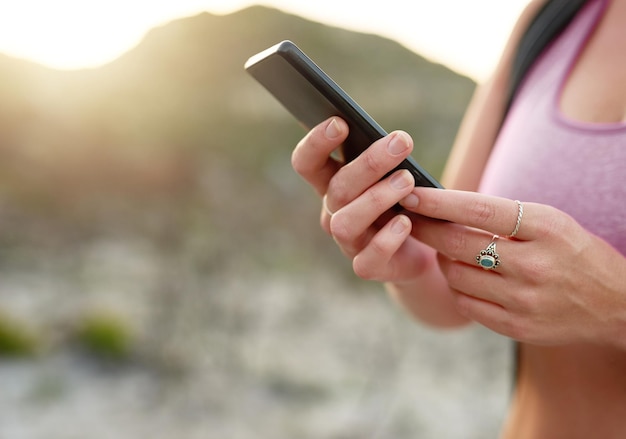 Haar telefoons gps gebruiken om haar wandelroute te plannen close-up shot van een onherkenbare vrouw die haar telefoon gebruikt tijdens een wandeling