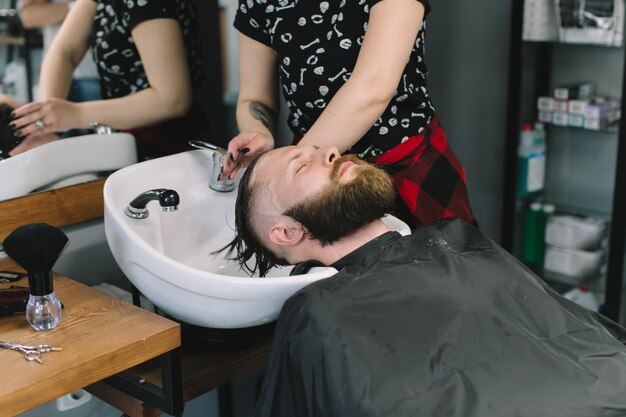 Haar voor haarstylist cliënt wassen in kapperszaak.