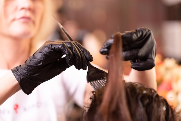 Haarkleuring in de salon haarstyling Professionele tovenaar schildert het haar in de salon Schoonheidsconcept haarverzorging