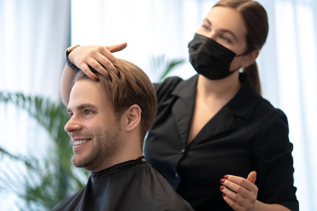 Haarstylen. Blonde man met hairstyling procedures in de schoonheidssalon