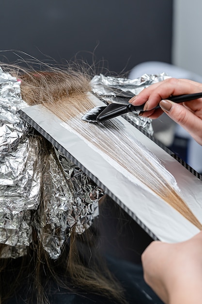 Haarstylist bleekpoeder op het haar van klanten toe te passen en in de folie te wikkelen. Shatush-techniek