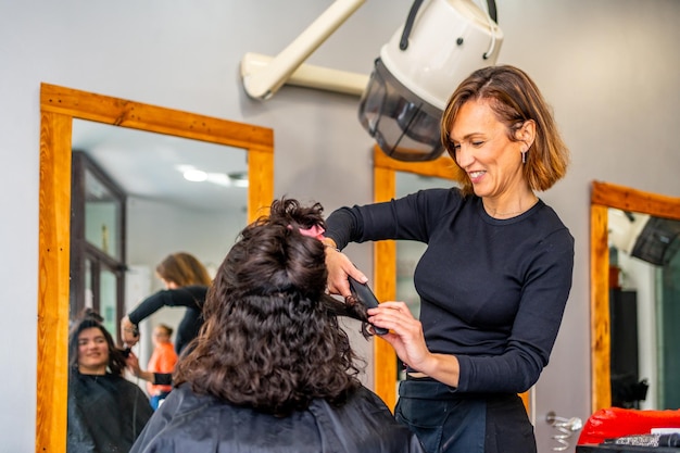 Foto haarstylist die het haar van een klant strijkt in een salon