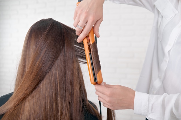 Haarstylist die met het bruine haar van de cliënt werkt.