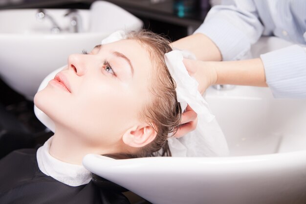 Haarstylist drogen vrouwenhaar met handdoek in salon