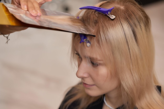 Haarstylist maakt bouffant met behulp van kam op dunne strengen shatush-techniek voor haarverlichting