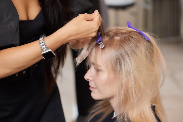 Haarstylist maakt bouffant met behulp van kam op dunne strengen Shatush-techniek voor haarverlichting