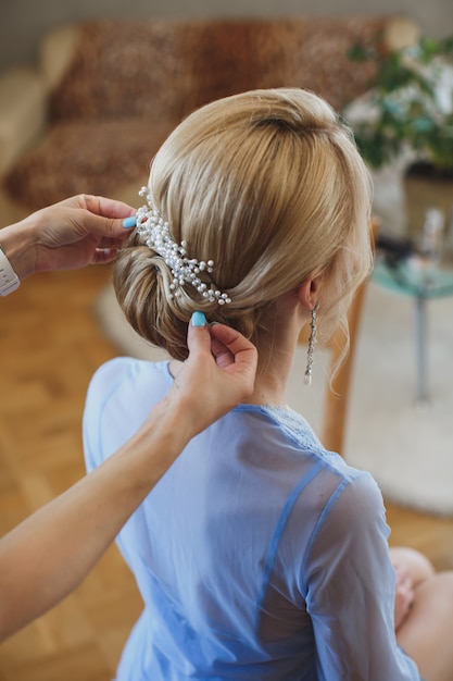 Haarstylist maakt van de bruid een bruidskapsel met verse bloemen