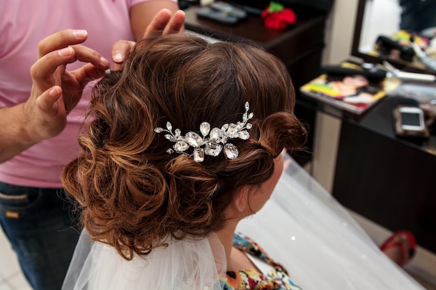 Haarstylist of bloemist maakt van de bruid een bruiloftskapsel