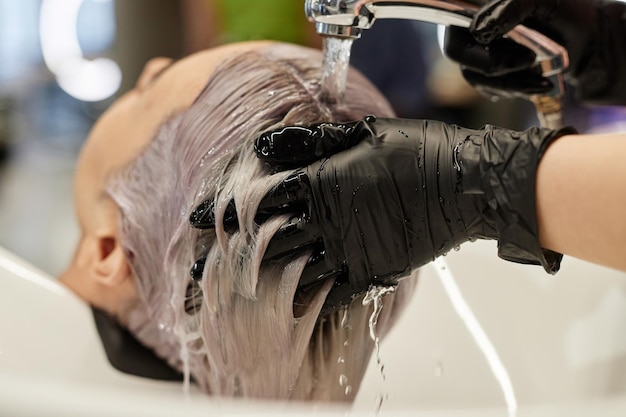 Haarstylist wast het haar van een jonge vrouw in de salon